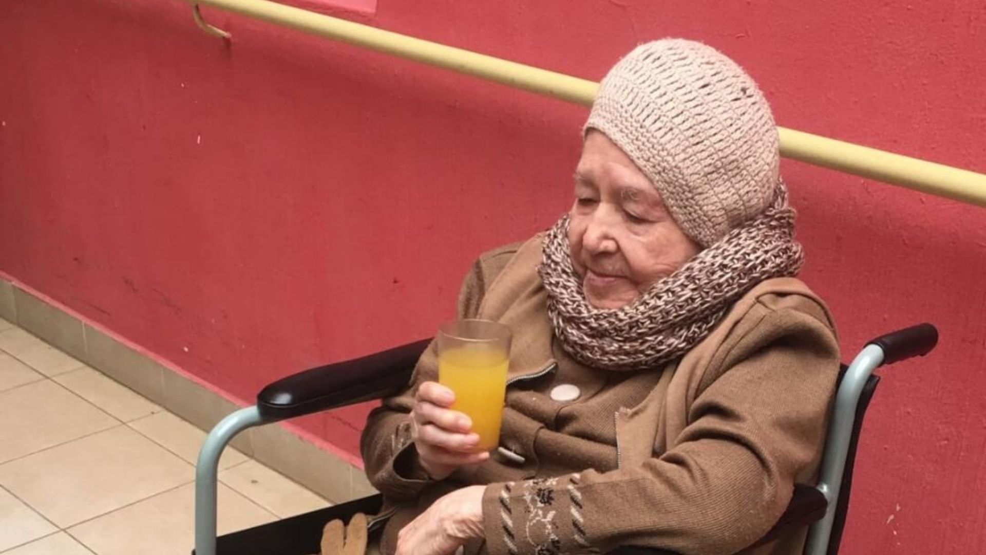 thumbnail of elderly woman sitting in a wheelchair and drinking orange juice