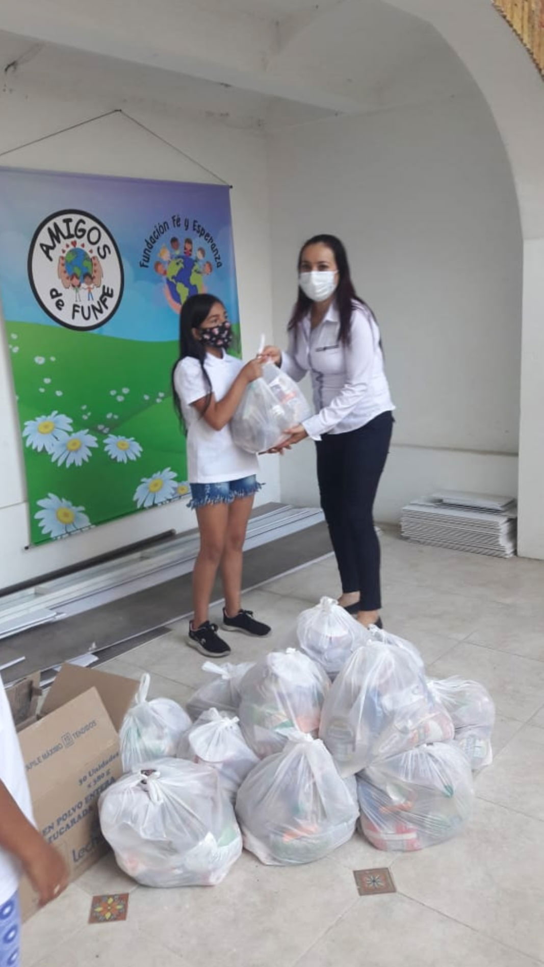 a teacher giving a bag of food to a young girl